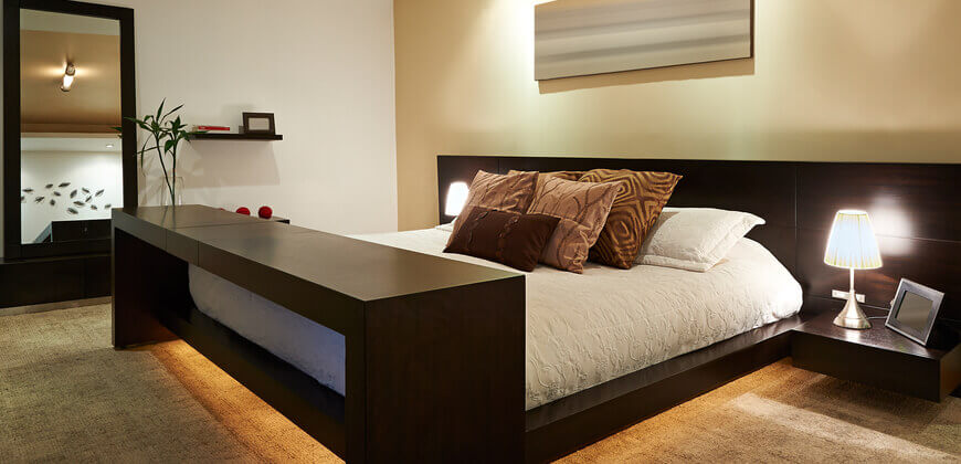 Image of bedroom with relaxing lighting surrounding the bed. 