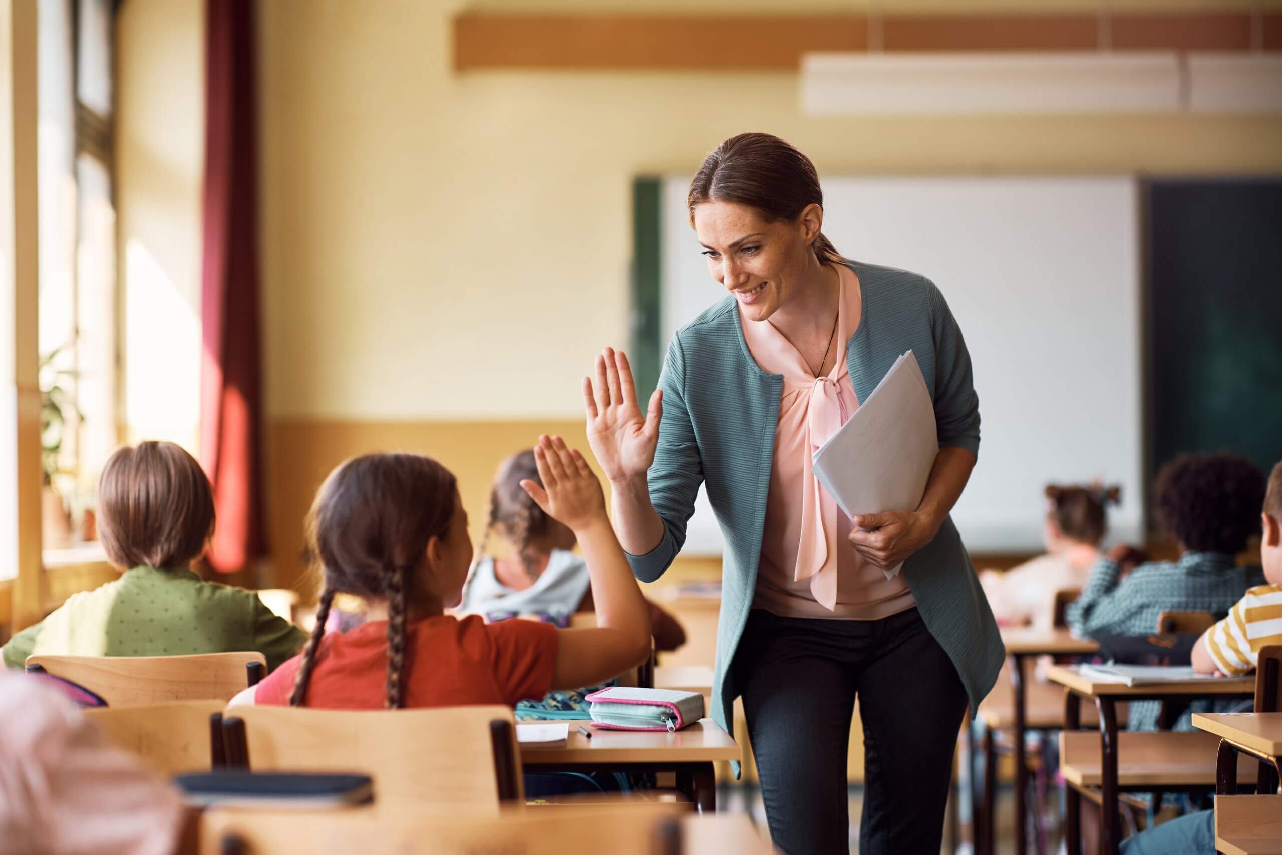 A teacher high fivinh a school child in a classroom in a school in Basingstoke.