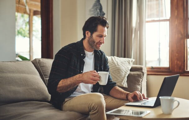 A man sitting on the sofa, with a cup of tea in his hand as he works from home in Swindon.